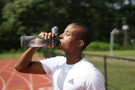 Person drinking water to stay hydrated while using a creatine supplement